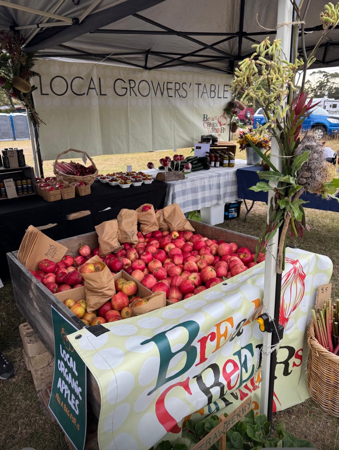 A crate of local organic apples under a Local Growers Table sign at Bream Creek Farmers Market